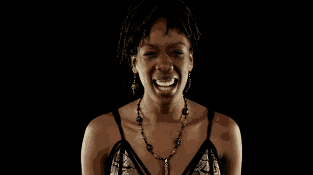 a woman with dreadlocks and a necklace laughs