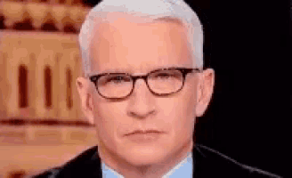 a man wearing glasses and a suit is making a face .