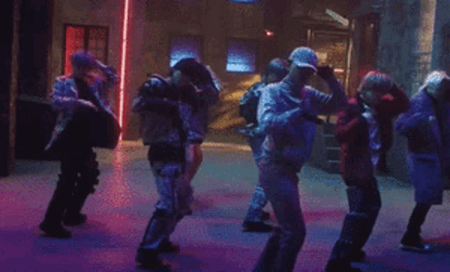 a group of people are dancing in a dark room .