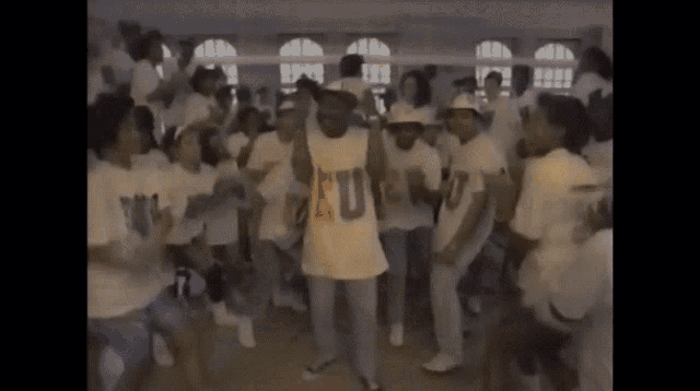 a group of people are dancing and one of them is wearing a shirt that says u
