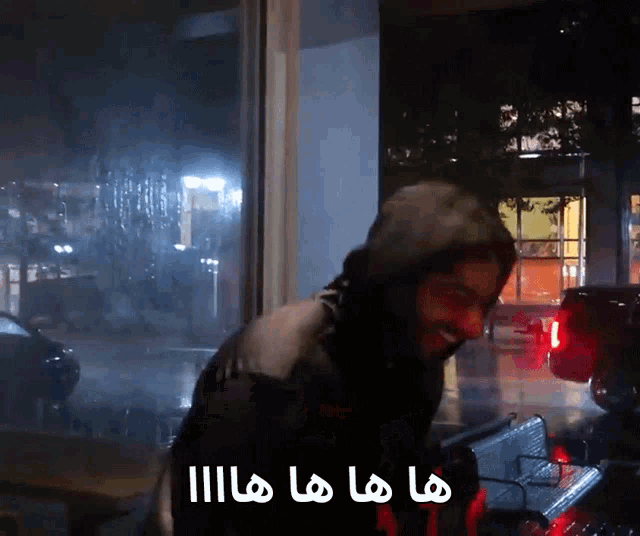 a man standing in front of a window with arabic writing on the bottom