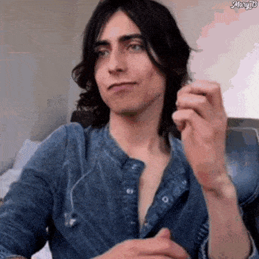 a man with long hair is wearing a denim shirt and headphones