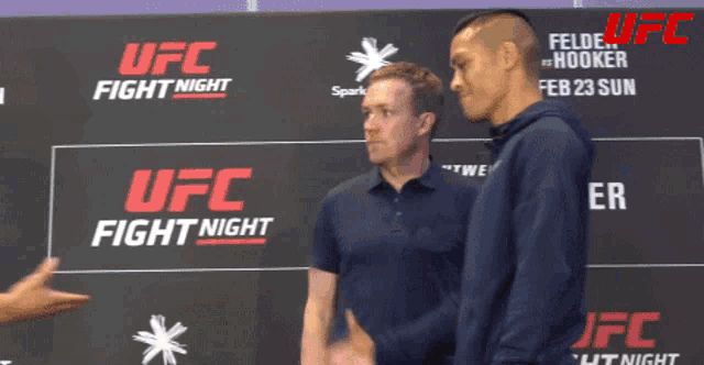 two men are shaking hands in front of a sign that says ufc fight night