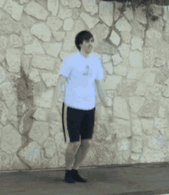 a man in a white shirt and black shorts is jumping in the air