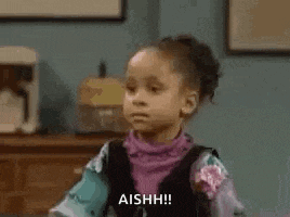a little girl is sitting in front of a table and making a face .