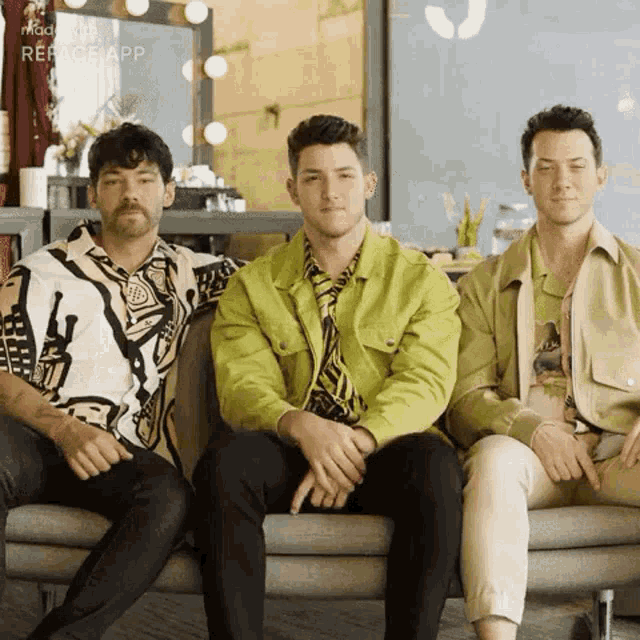 three men are sitting next to each other on a couch