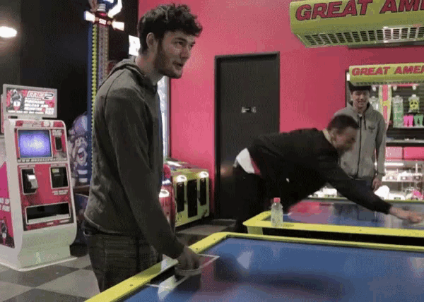 a man is playing air hockey in front of a great america sign