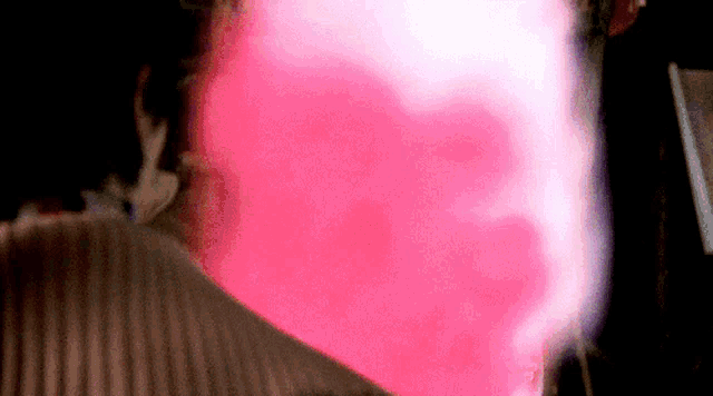 a blurred image of a person 's face with a pink background