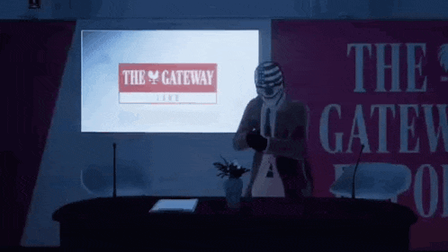 a man stands in front of a screen that says the gateway