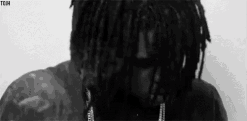 a black and white photo of a man with dreadlocks and chains .