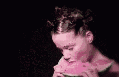 a woman is eating a slice of watermelon with her eyes closed .