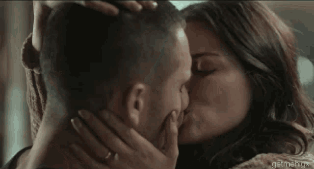 a man and a woman are kissing each other in a room .
