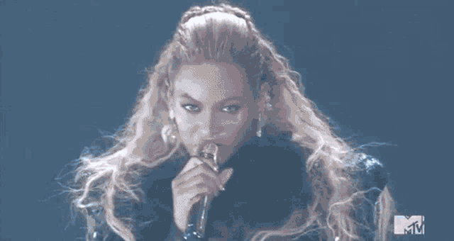 a woman is singing into a microphone on stage .