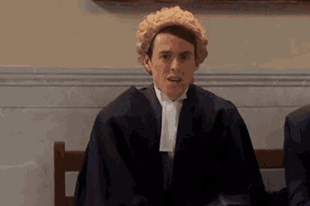 a man in a wig is sitting in a chair