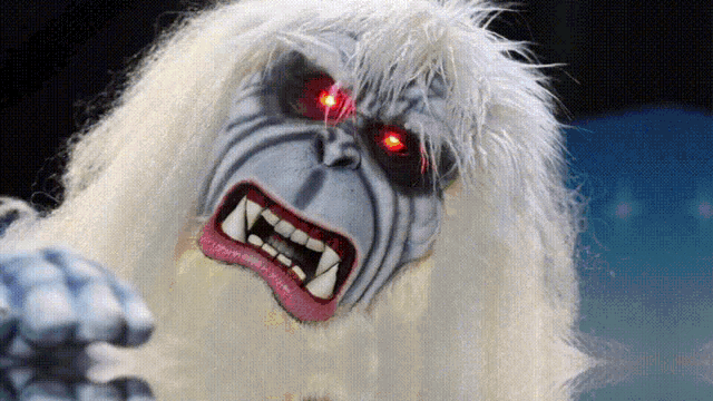 a yeti with red eyes and sharp teeth is looking at the camera
