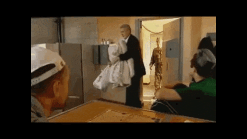 a man in a suit is standing in a doorway holding a bag .