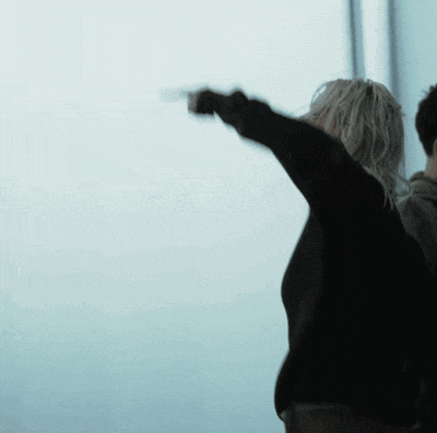 a woman in a black sweater points to the sky