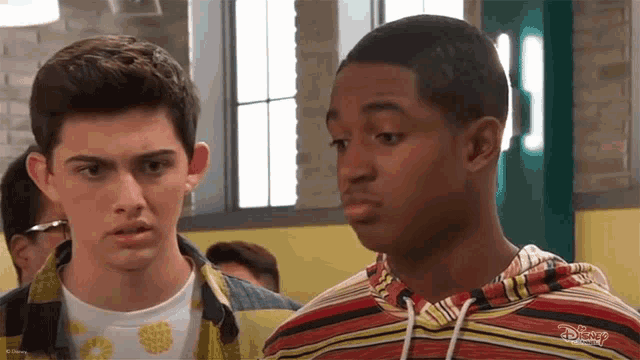 two boys are standing next to each other and one of them is wearing a disney shirt