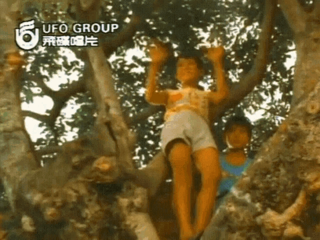 a girl is climbing a tree with a ufo group logo on the bottom