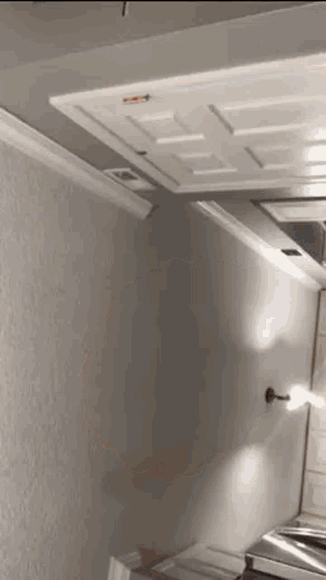 a room with a ceiling fan , a door , a light , and a stove .