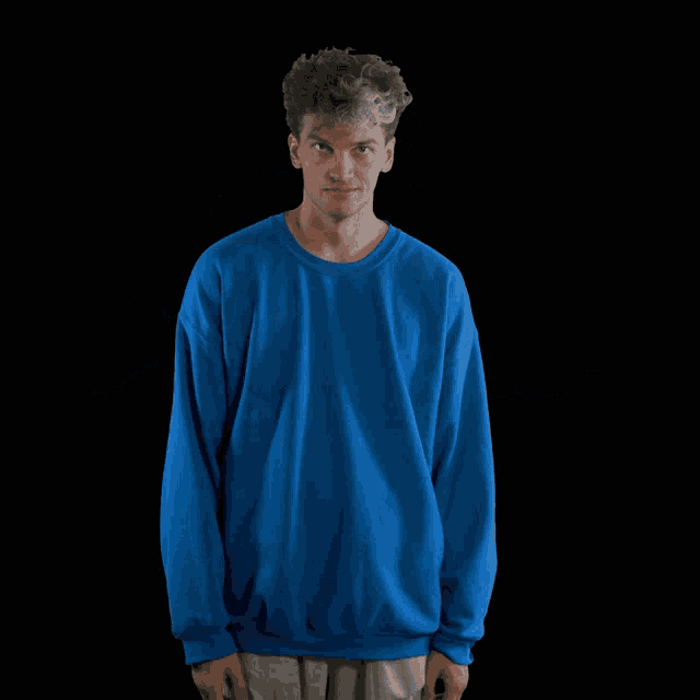 a man wearing a blue sweatshirt with his hands outstretched