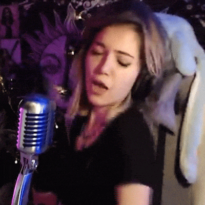 a woman singing into a microphone with headphones