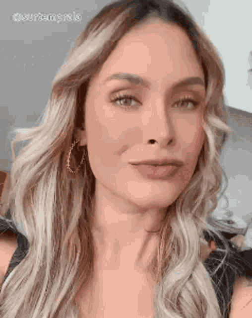 a close up of a woman 's face with long blonde hair and earrings .