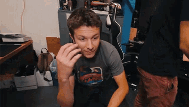 a man wearing a t-shirt that says ' spiderman ' on it talking on a cell phone