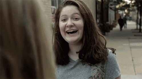a young woman is smiling while talking to another woman on a city street .