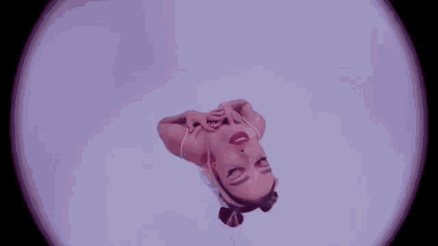 a woman is laying on her back in a purple room with her head upside down .