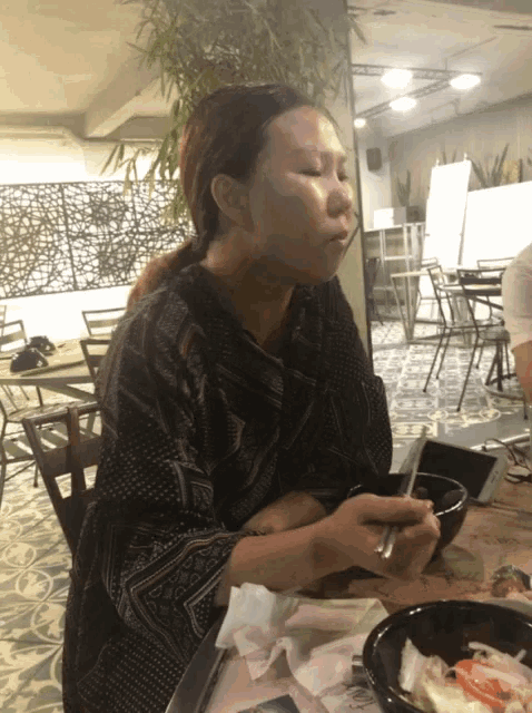 a woman sitting at a table with a bowl of food in front of her