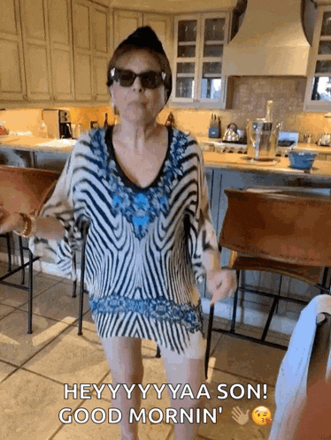 a woman wearing sunglasses and a striped shirt is dancing in a kitchen