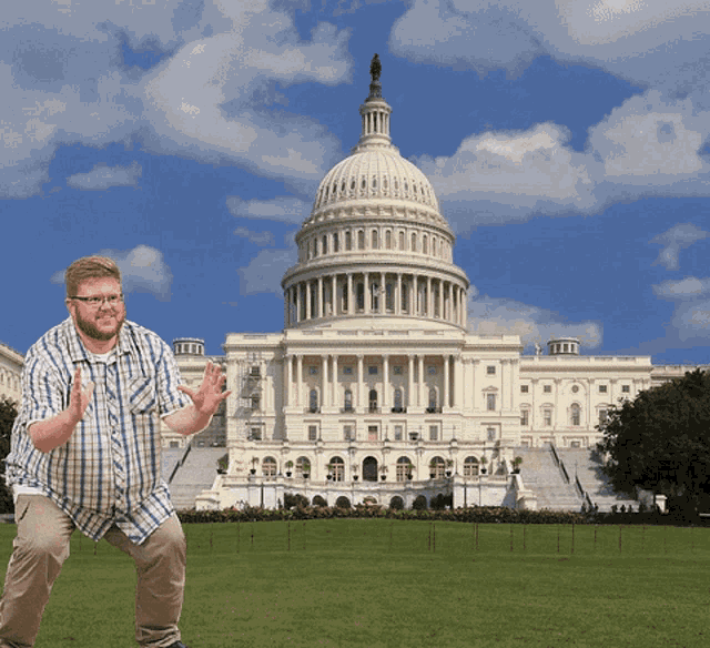 a man stands in front of the capitol building with his hands up