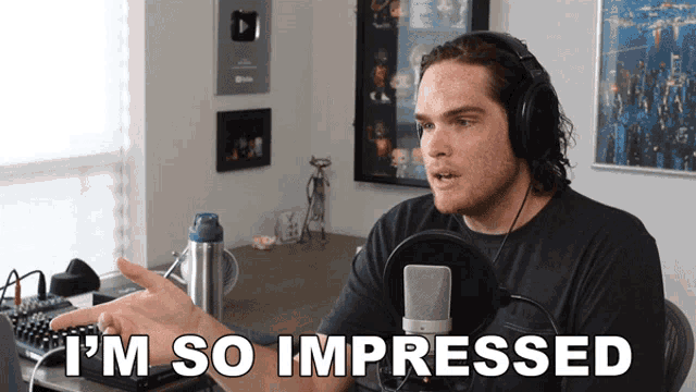 a man wearing headphones says " i 'm so impressed " while sitting in front of a microphone