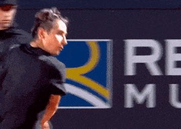 a man is swinging a tennis racket in front of a remu logo