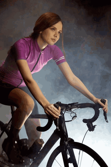 a woman in a purple shirt rides a bike