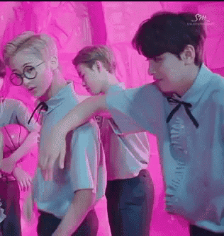 a group of young men are standing in front of a pink wall .