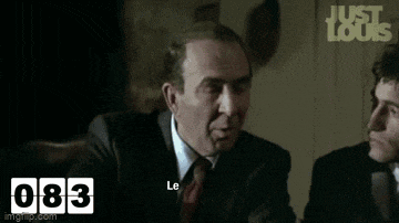a man in a suit and tie is talking to another man in a suit and tie while sitting at a table .