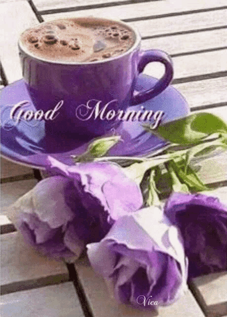 a cup of coffee is on a saucer next to purple flowers and the words good morning