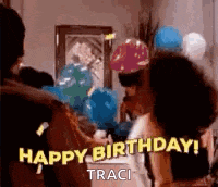 a group of people are celebrating a birthday with balloons and a woman is saying `` happy birthday ! ''
