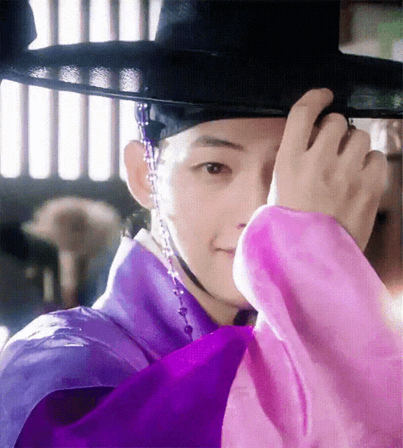 a close up of a person wearing a hat and a purple robe