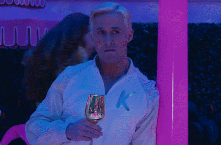 a man holding a glass of wine with the letter k on his jacket