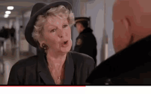 a bald man and a woman are talking in a hallway .