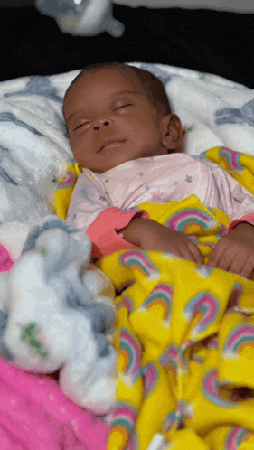 a baby wrapped in a yellow blanket with rainbows on it