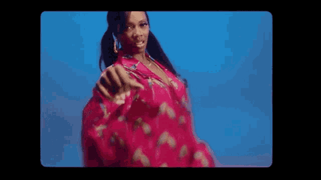 a woman in a pink dress is dancing on a blue background in a video .