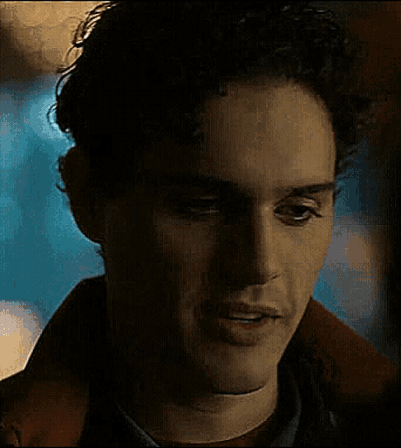 a close up of a man 's face with a red shirt and a brown jacket