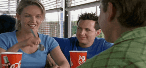 a man and a woman sit at a table with coca cola cups in front of them