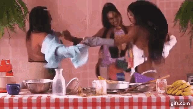 three naked women are standing around a table with a checkered table cloth ..