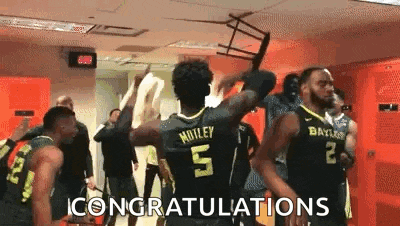 a group of basketball players are standing in a locker room celebrating a win .