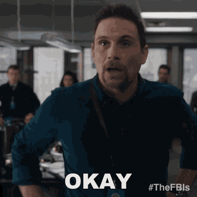 a man in a blue shirt says okay in front of a group of people